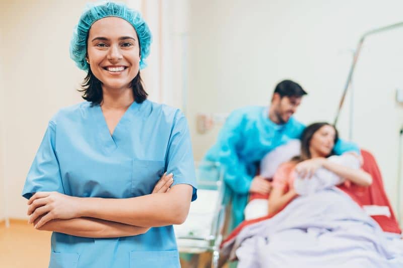 Happy midwife in front of a young family with a newborn baby. Happy midwife in front of a young family with a newborn baby.