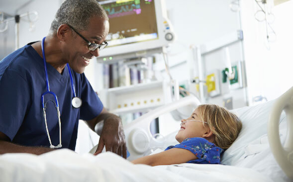 senior healthcare professional smiling and talking with pediatric patient in bed